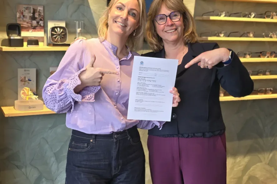 Twee medewerkers van Von Oy staan lachend in de winkel, een van hen houdt een document omhoog