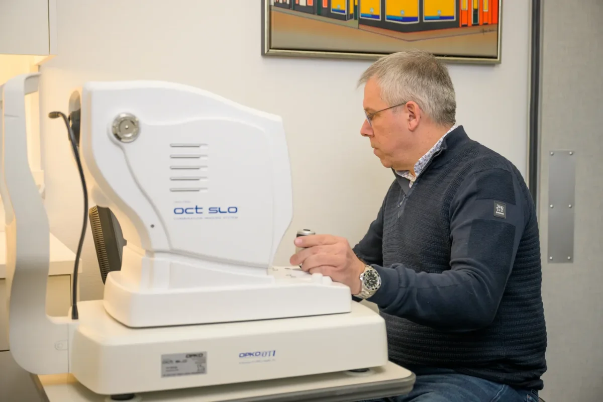 Opticien Cris achter de OCT-scanner waarmee het netvlies in beeld komt
